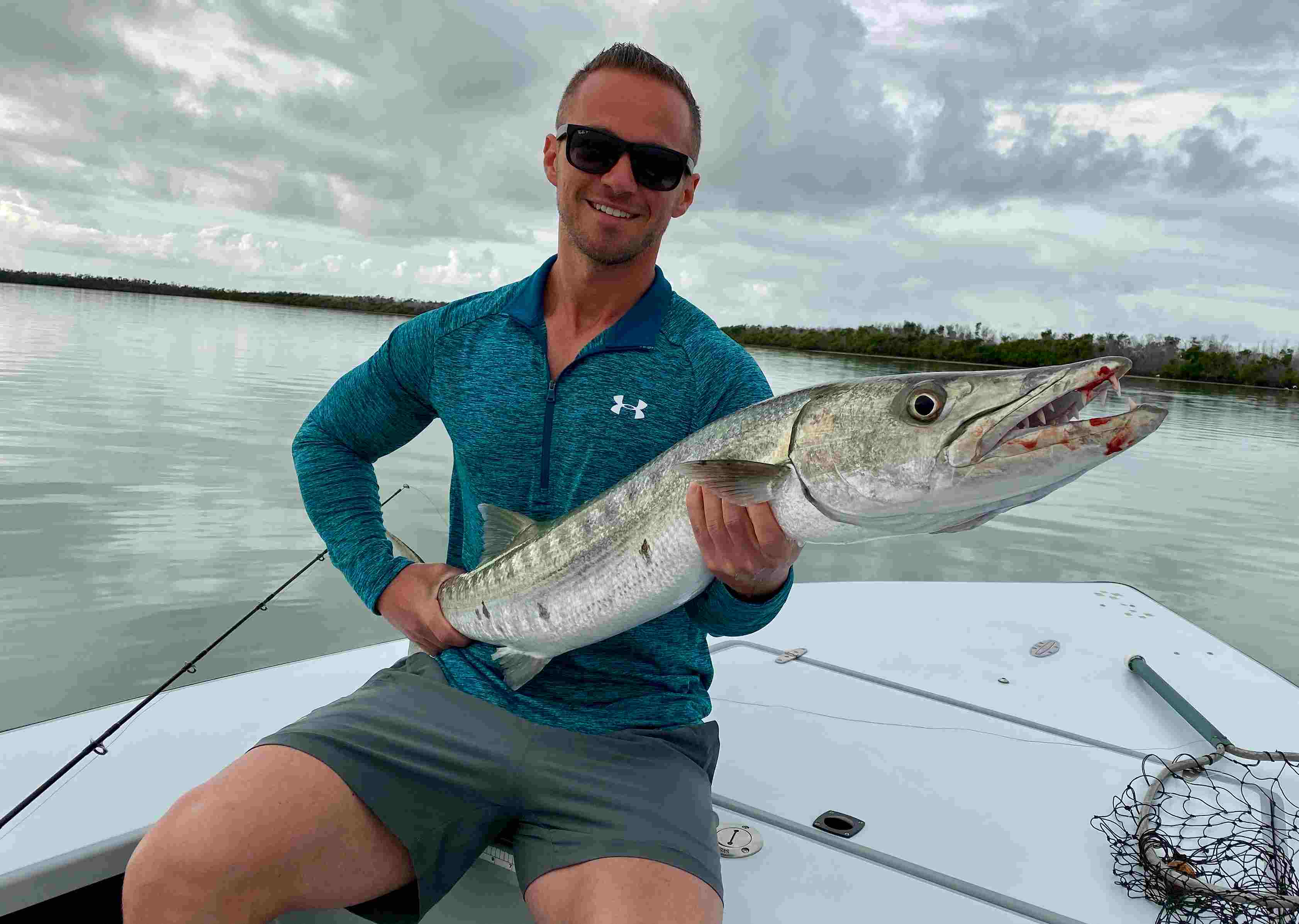 A fisherman holding a big barracuda while on a florida Keys flats fishing charter