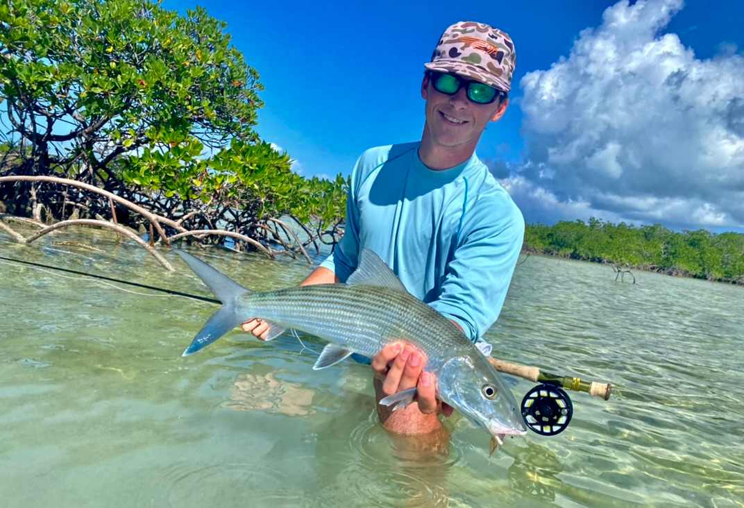 Fisherman in the Florida Keys flats with a bonefish on fly